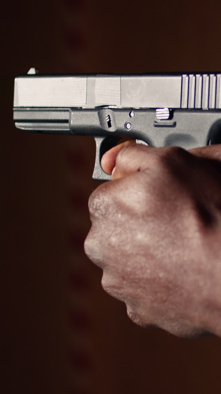 Vertical video Man holding pistol at indoor shooting range, close up