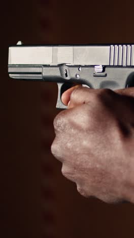 vertical video man holding pistol at indoor shooting range, close up