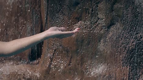 lady catches water drops falling from artificial waterfall