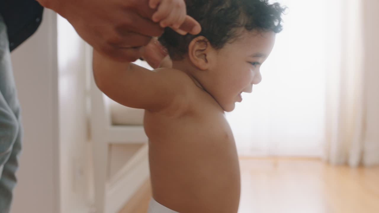 beautiful baby learning to walk toddler taking first steps with parent helping infant teaching child at home