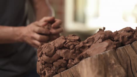 a close-up of a sculptor preparing material clay for pottery. man is taking and shaping clay for creating ceramic statue in studio. selective focus shot