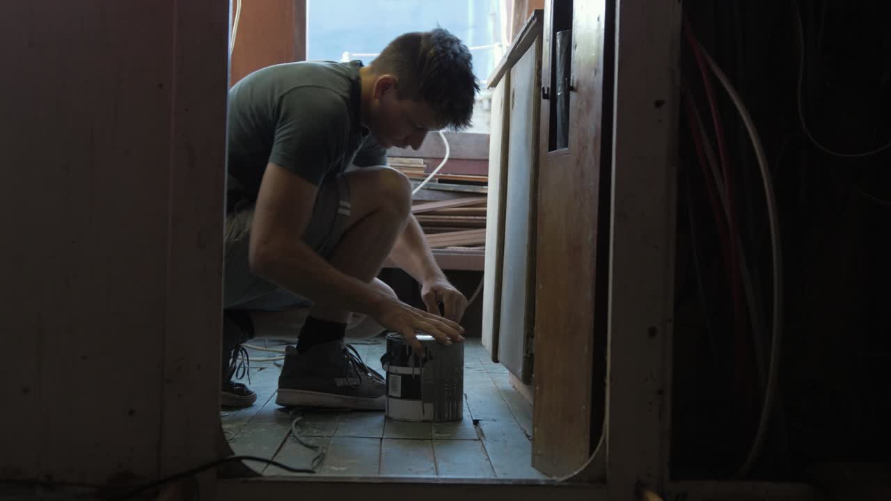 joven tomando una lata de pintura de la prensa