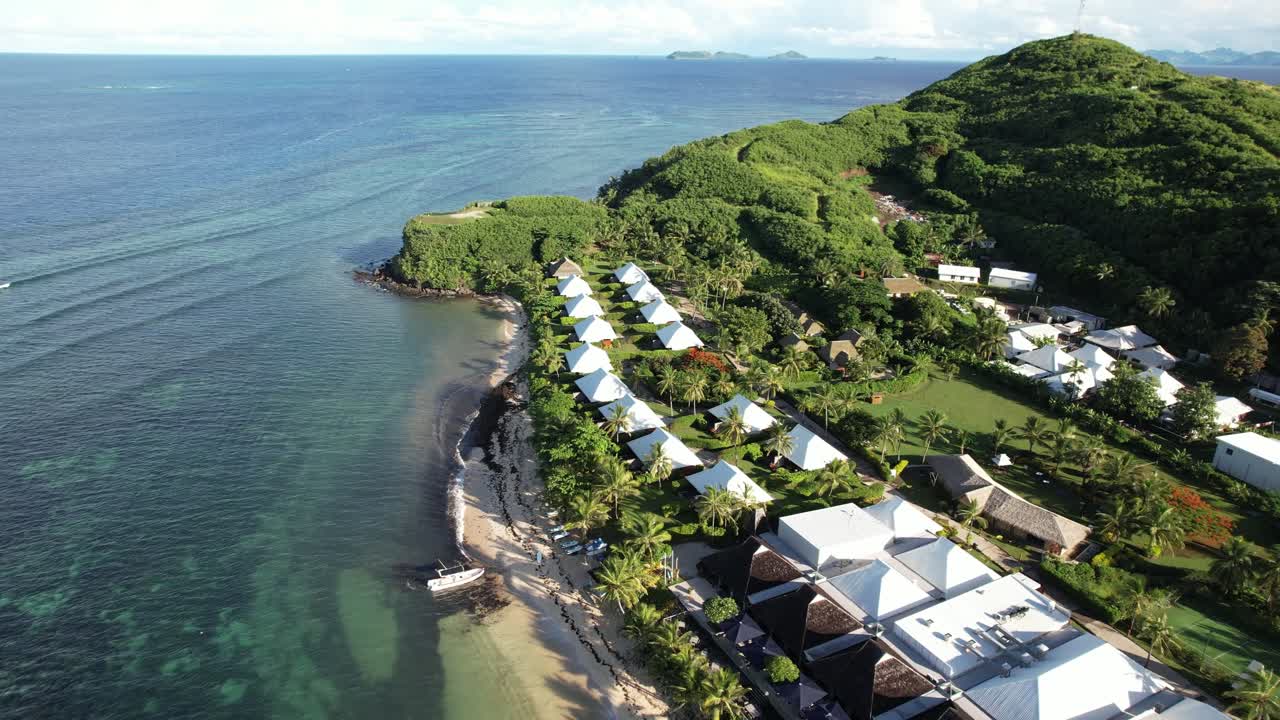 Midday aerial pullback over beachfront bungalows and clear water at Tokoriki Island, Fiji