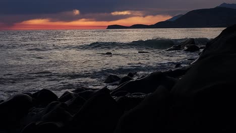 Noche-En-La-Costa-Del-Mediterráneo-Con-Un-Cielo-Rojo-Nublado-Que-Se-Refleja-En-La-Superficie-Del-Mar-Oscuro,-Romántico-Crepúsculo-De-Verano