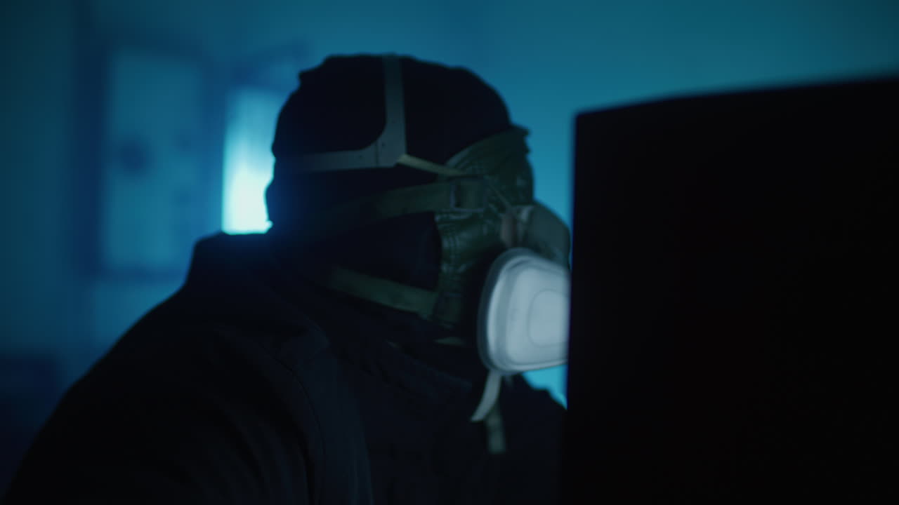 Masked Person at a Computer in the Dark
