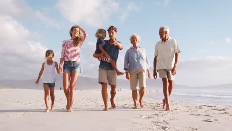 multi generation family on summer vacation walking along beach