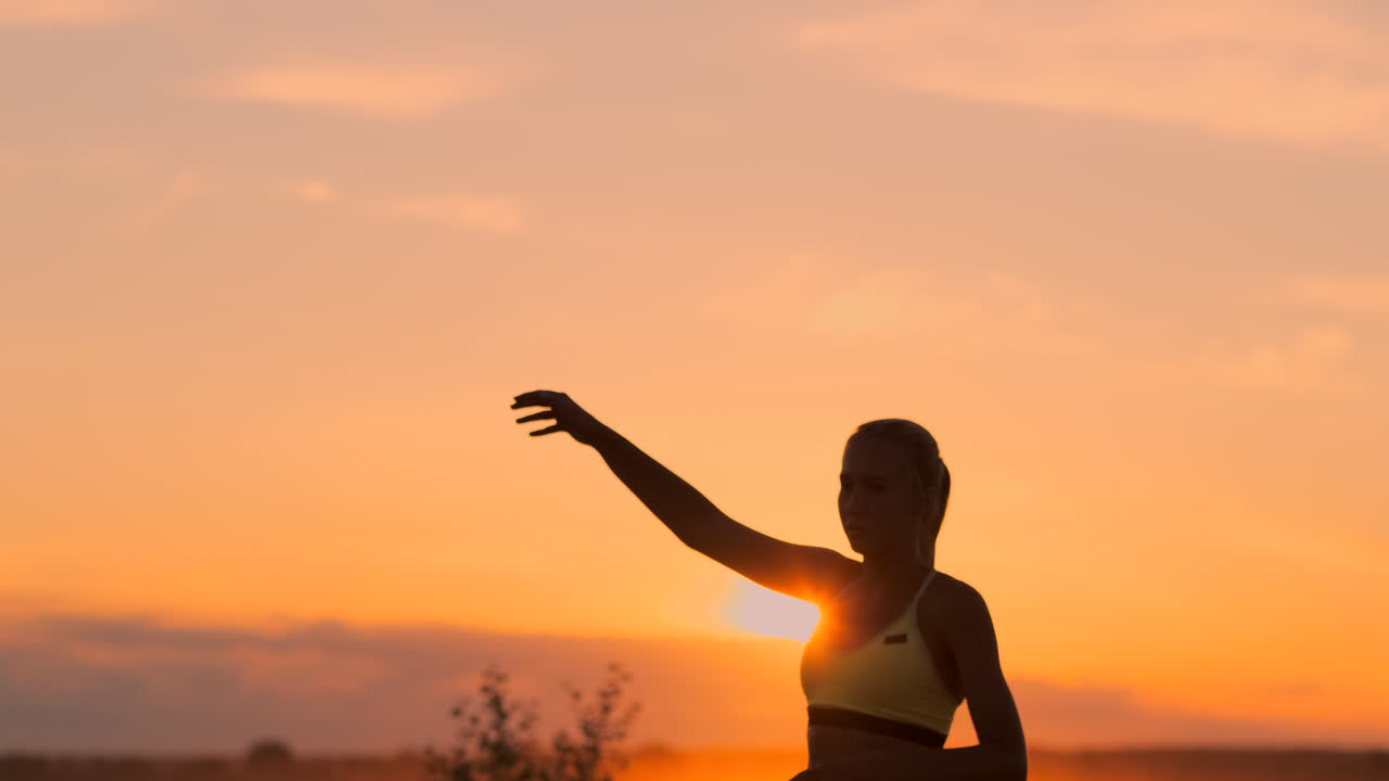 Medium shot van een vrouwelijke volleybalster bij zonsondergang die de bal terugslaat in slow motion.
