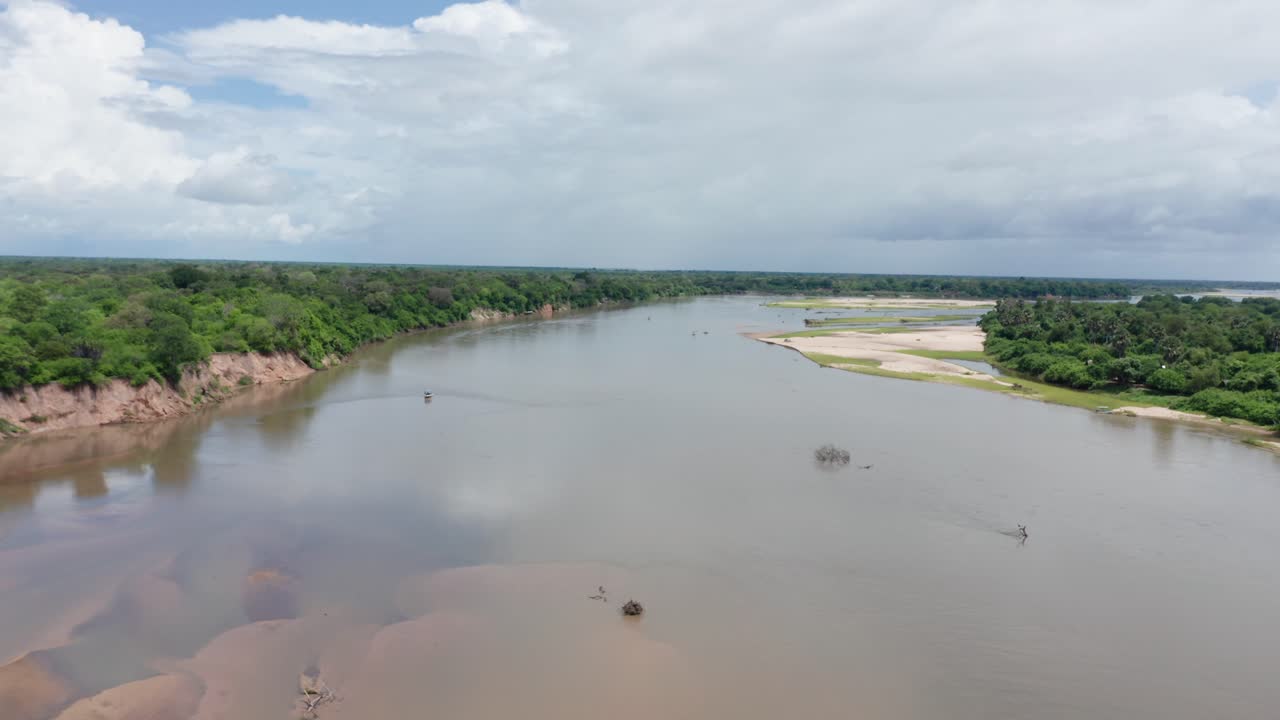 Aerial drone shot flying sideways over a river in Selous, Tanzania, surrounded by dense vegetation