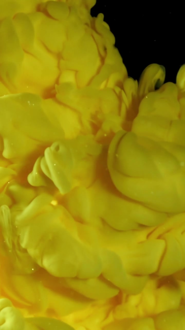 Inchiostro giallo vivace che si diffonde e si mescola nell'acqua su sfondo nero