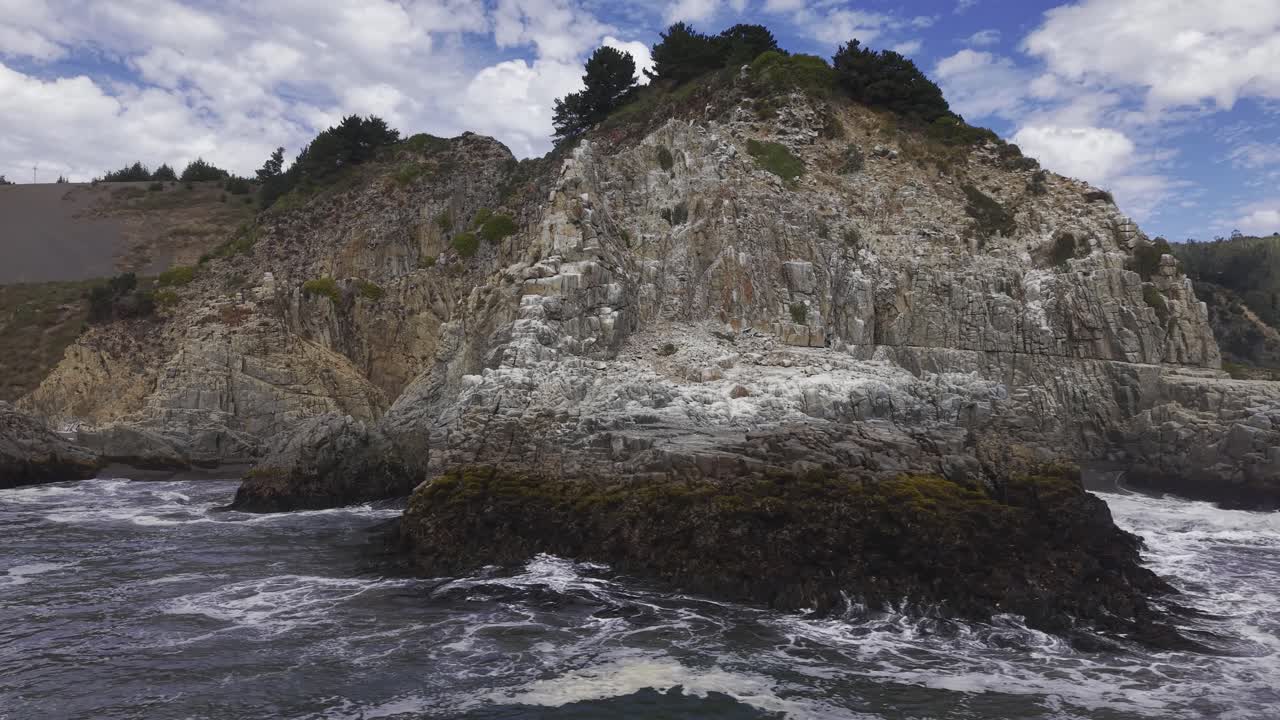 Vista aerea ravvicinata che circonda Piedra del Elefante a Constitución, Cile, una ripida scogliera rocciosa sopra un mare agitato con onde che lambiscono la base rocciosa, 4K.