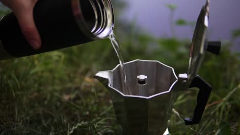 Making-coffee-at-a-camping-trip-by-pouring-hot-water-inside-a-coffee-can-with-powder-in-it