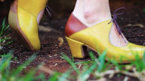 woman wearing high hills flamenco shoes , high hill shoe stepping on wet soil, white legs of a woman wearing high hills shoes with ropes tired on