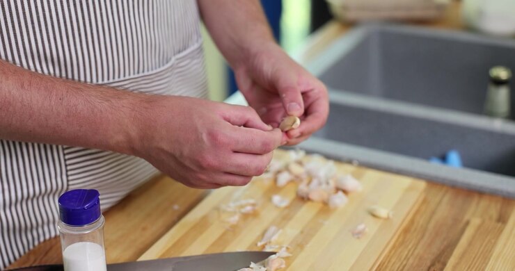 Chef esperto rimuove lo strato esterno di uno spicchio d'aglio