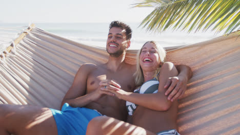 Caucasian-couple-lying-on-a-hammock-on-the-beach