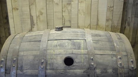 close up of a disused, empty oak scotch whisky barrel on it's side with a cork resting on the top under artificial light