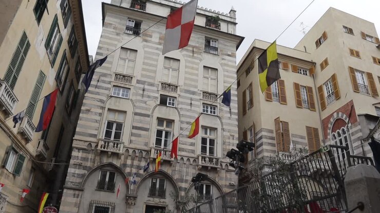 Inquadratura dal basso verso l'alto che mostra un alto edificio tradizionale a strisce con molteplici festoni di bandiere multicolori.
