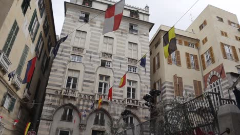 Tilted-upward-looking-shot-showing-tall-striped-traditional-building-with-multiple-strings-of-multicoloured-flags