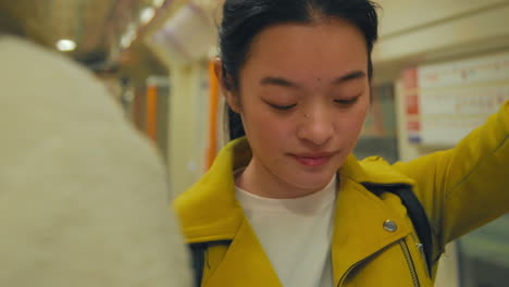 지하철에서 일하러 가는 젊은 여성이 휴대전화를 확인하고 있다.