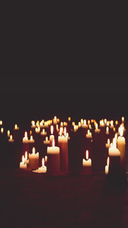 a collection of lit candles in the darkness