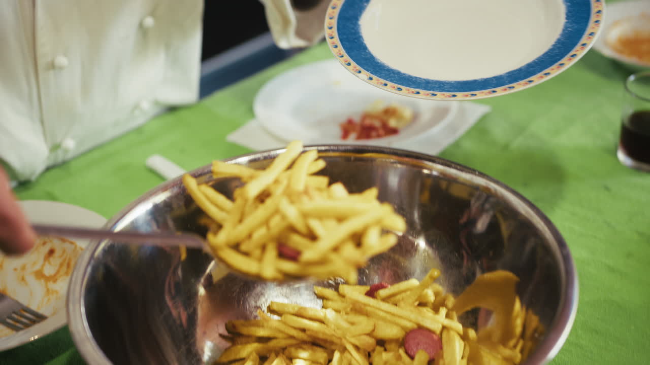 Chef Is Portioning French Fries and Sausages onto Plates in an Italian Cooking