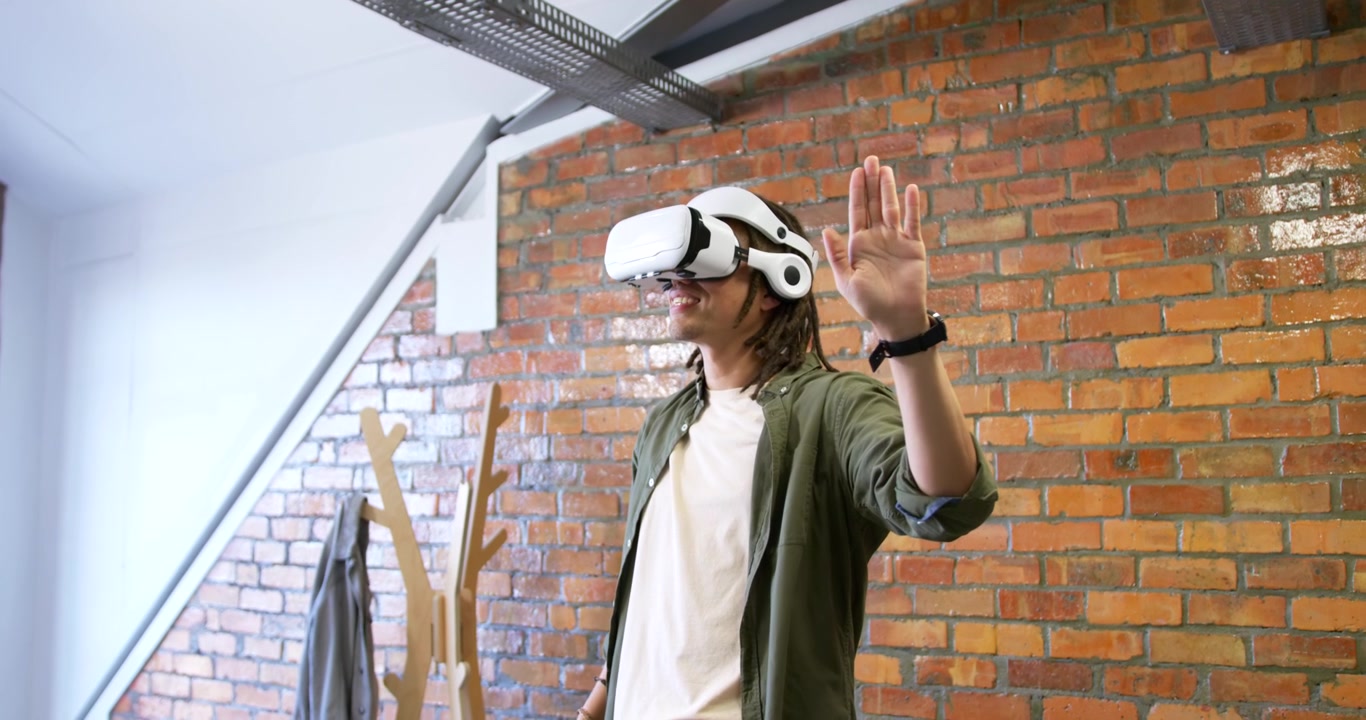Uomo afroamericano con visore VR bianco in un loft, che si allunga, pizzica, ruota e reagisce a input.