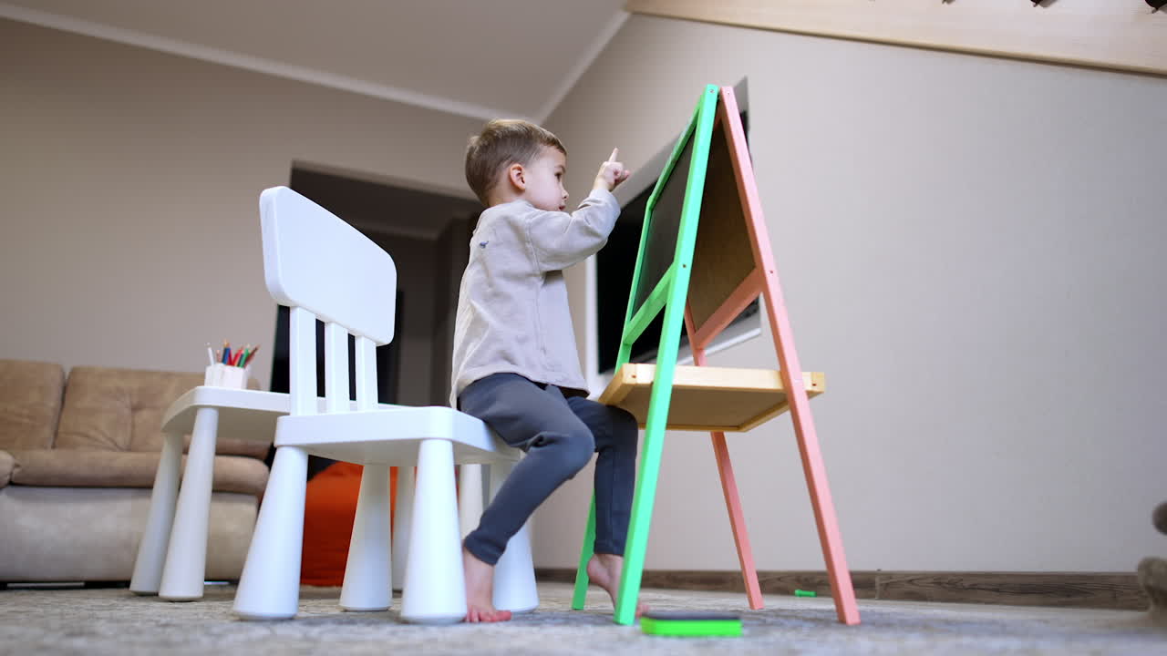 Child engaging with an art easel indoors. A young child is focused on creating art at an easel in a cozy indoor space during the afternoon