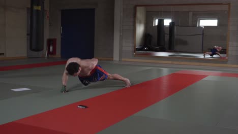 sesión de entrenamiento con kickboxer ruso y armenio haciendo flexiones con un brazo en el gimnasio