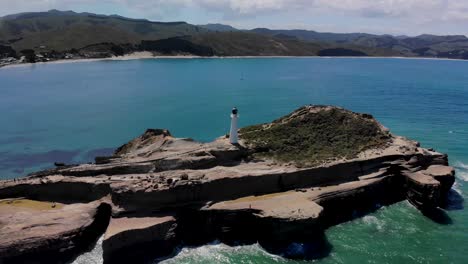 Aerial-view-of-Castlepoint-lighthouse-reveal-stunning-New-Zealand-coastal-scenery-during-sunny-day