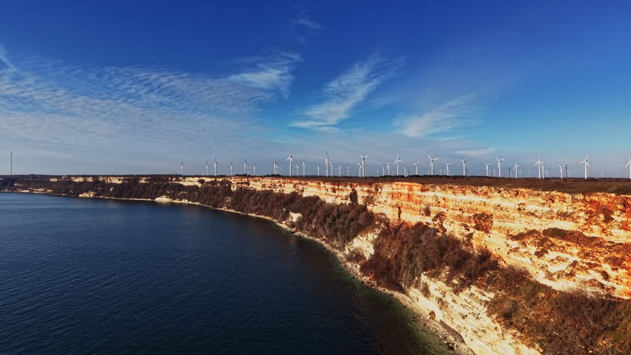 Aerogeneratori su scogliere vicino alla costa sotto un cielo blu