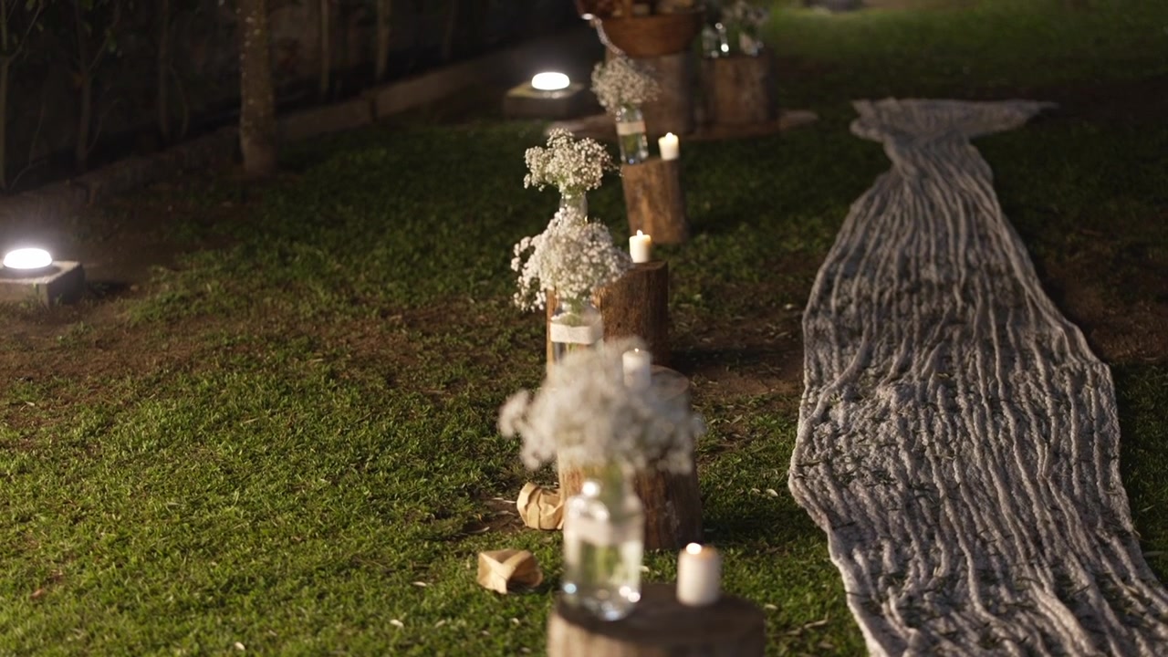 Rustic wedding decoration with candles glass jars and flowers on grass