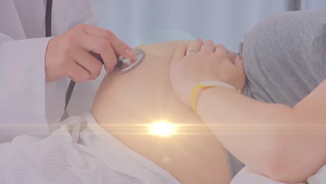 spot of light against close up of doctor checking tummy of caucasian pregnant woman