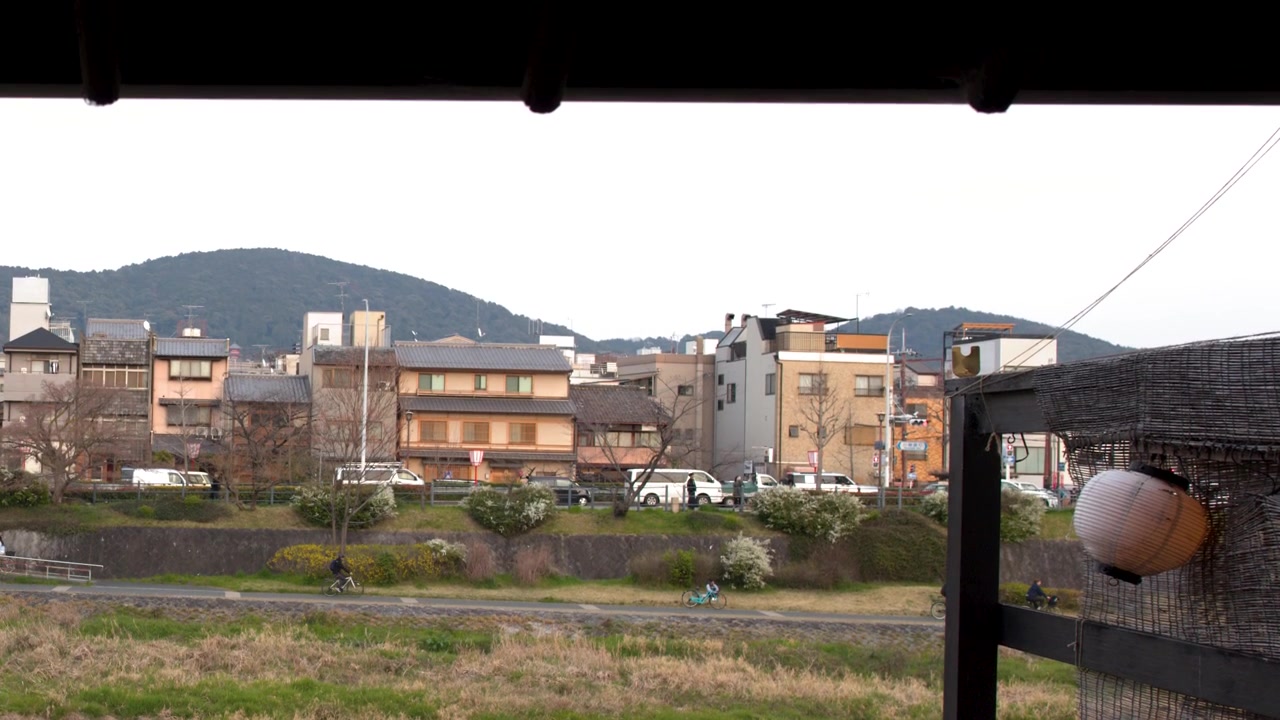 Ampia inquadratura della riva del fiume Kamo e degli edifici della città sotto le montagne a Kyoto, Giappone