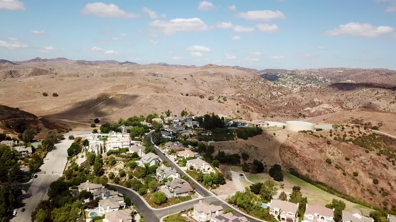 Exclusive Housing area and neighborhood of famous celebrities in Hidden Hills, California. Luxury villas on hilltop and mountain landscape in background. Drone forward wide shot.