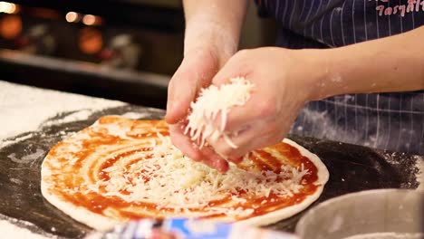 cheese being added to a pizza base