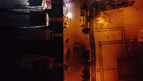 Aerial-top-down-shot-of-port-during-night-time-with-boats-docked-and-people-walking