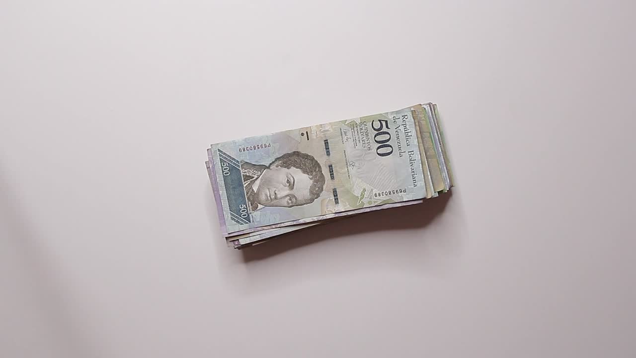 person drops five hundred bolivares on the table and another person picks it up and takes it, bribery, corruption