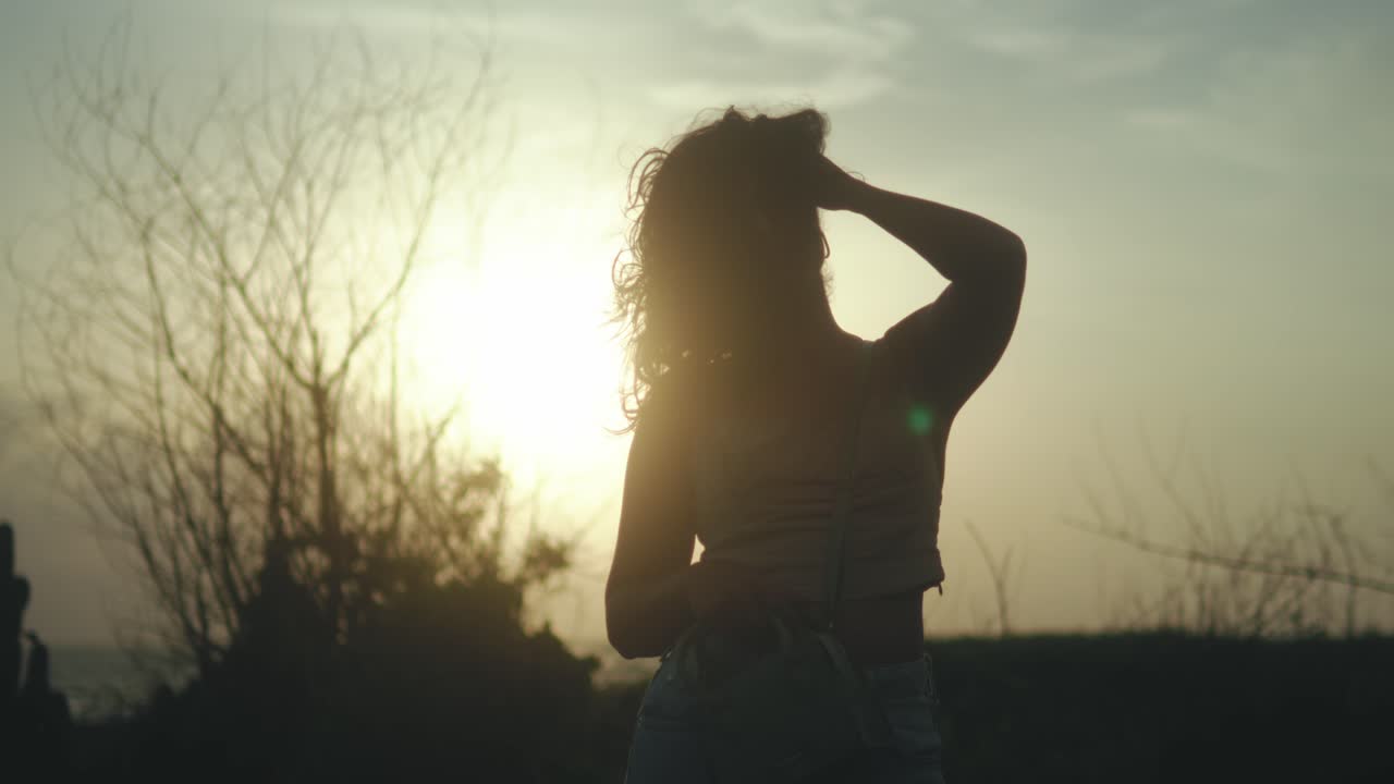 Silhouette di donna al tramonto, atmosfera rilassante, sfondo naturale.