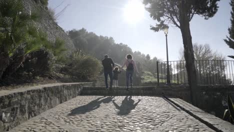 slow motion dolly shot of a family of mother and father with their small child on a viewing platform in medina sidonia during a sunny day