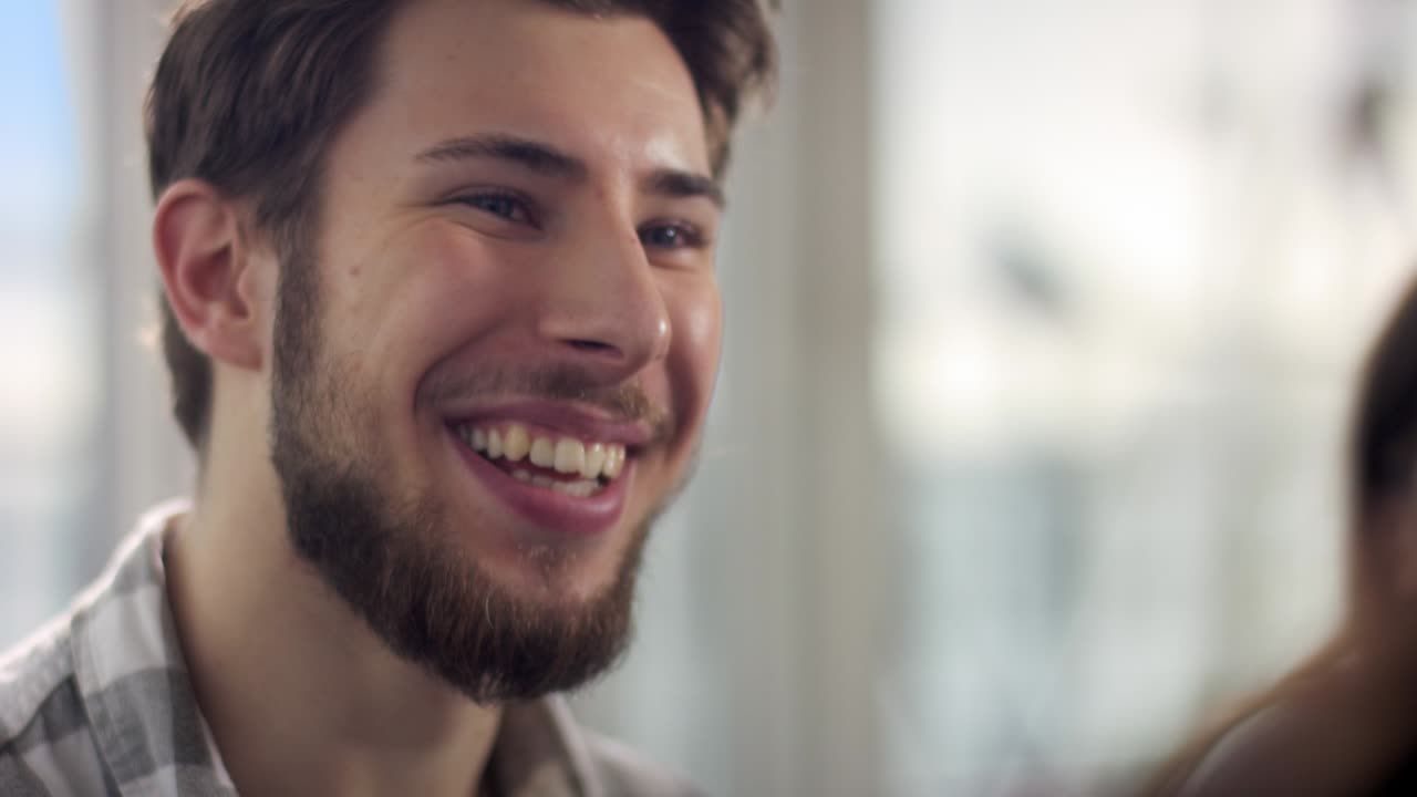 수염과 갈색 머리카락을 가진 자신감 있는 젊은 남자들이 방에서 여자와 이야기하고 있습니다.