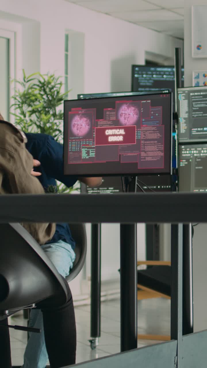 Vertical video: Diverse group of app developers working with hacked computer