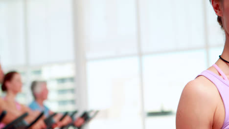 grupo feliz fazendo uma aula de spinning com o treinador sorrindo para a câmera