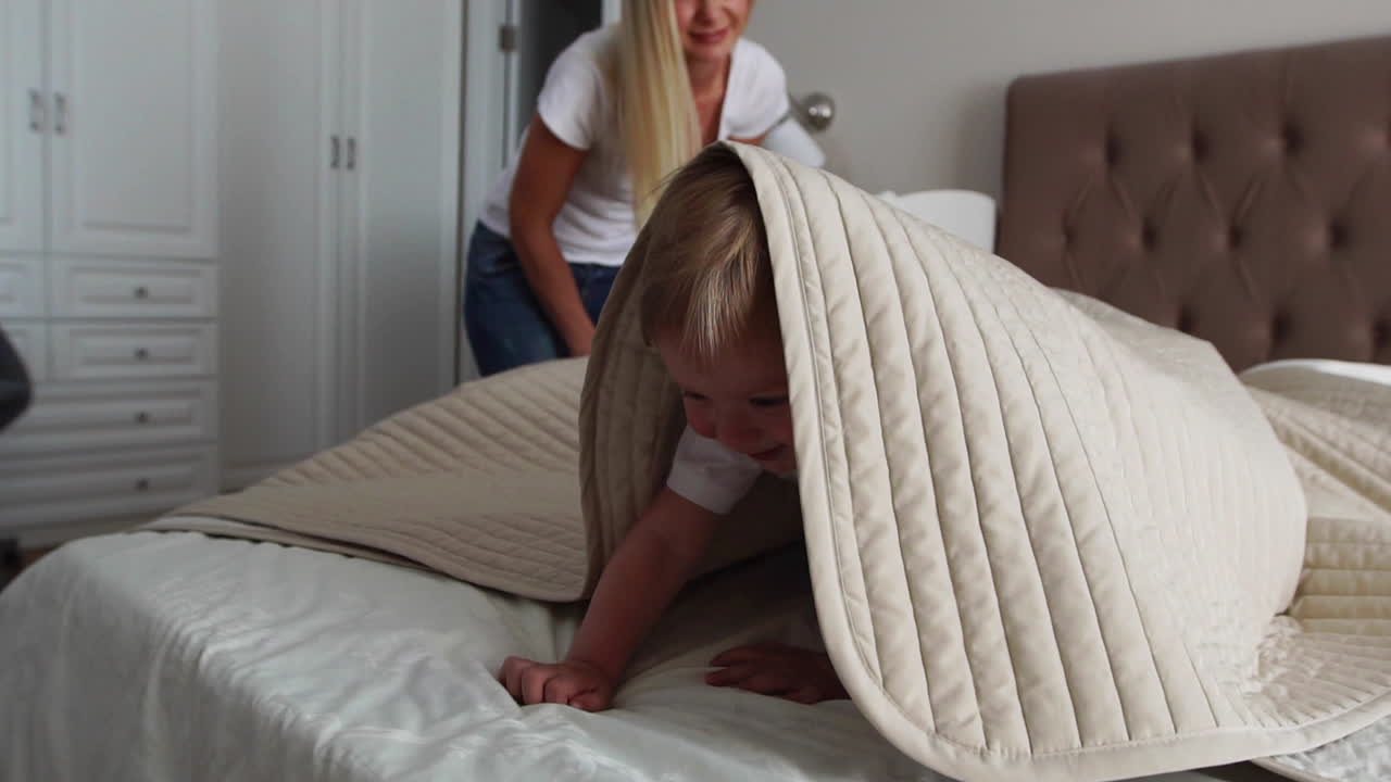 파자마를 입은 2살짜리 아들과 함께 어린 어머니와 아버지는 주말에 함께 침대에서 휴식을 취하고 놀고 있습니다. 게으른 아침, 따뜻하고 아 ⁇ 한 장면. 파스텔 색, 선택적인 초점.