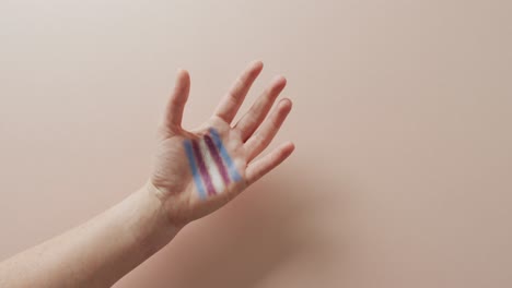 video of hand of caucasian man with rainbow flag on pink background