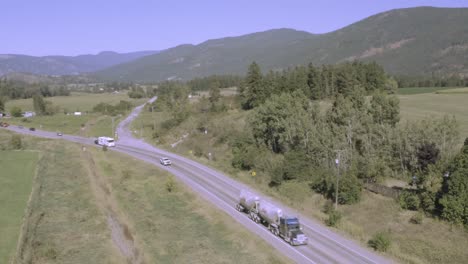 Autopista-Del-Valle-De-La-Montaña-Autopista-Interestatal-Siguiendo-Un-Camión-Cisterna-Doble-De-Combustible-Genérico-Blanco-Plateado-Transportador-De-Gas-Seguido-Por-Una-Casa-Rodante-Rv-Blanca-Remolcando-Un-Vehículo-En-Un-Día-Claro-Y-Caluroso-De-Verano-Mh1-2