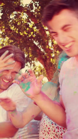 happy friends throwing powder paint in the park