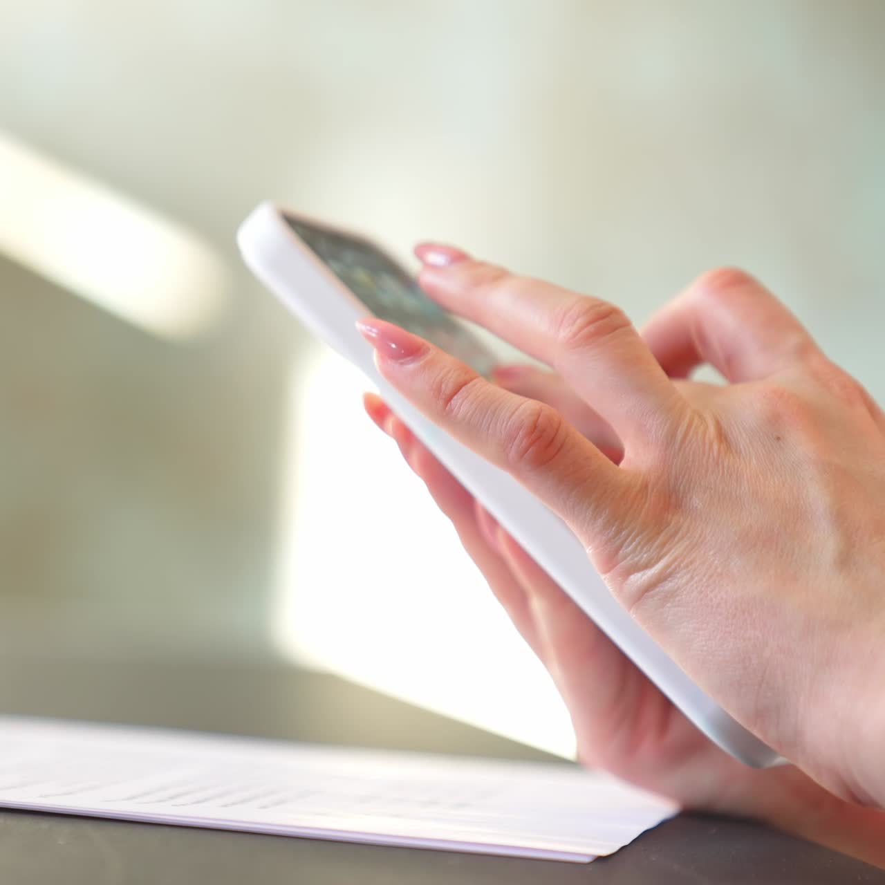 Woman presses gently on the telephone screen to take a picture of a document. Female hands rise the phone to look at the shot closer