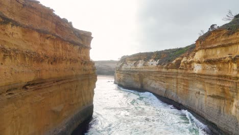 drone footage captures the dramatic cliffs and turbulent ocean waves of port campbell, australia, under bright daylight