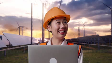 close up of asian female engineer with safety helmet working on a laptop and looking around with solar panel and wind turbines