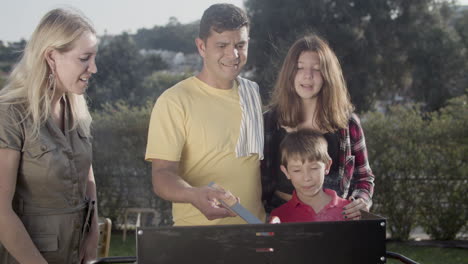 familia feliz cocinando verduras en la parrilla de barbacoa al aire libre