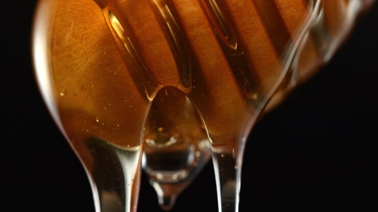 Close-up of Honey Dripping from a Honeycomb Dipper
